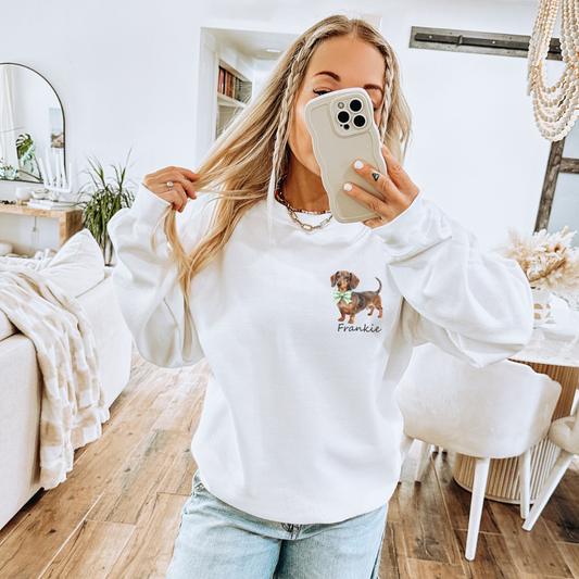 Woman taking a mirror selfie wearing a white sweatshirt with a dog graphic and text.