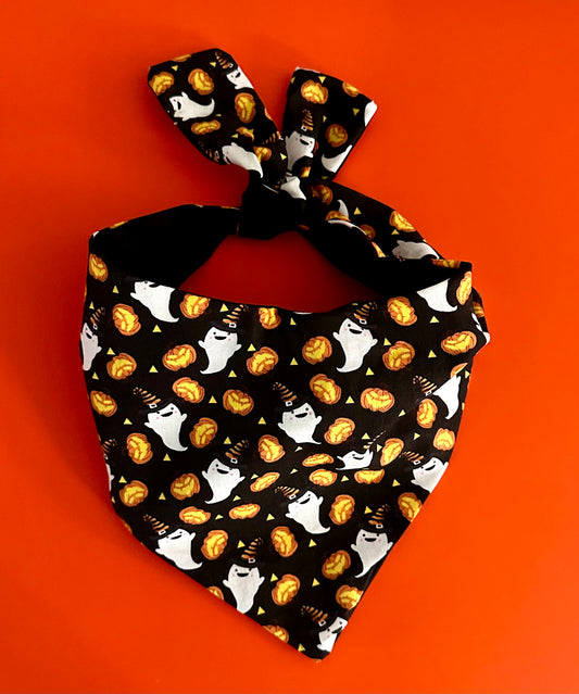 Halloween-themed bandana with ghosts, cats, and pumpkins on a black background against an orange background