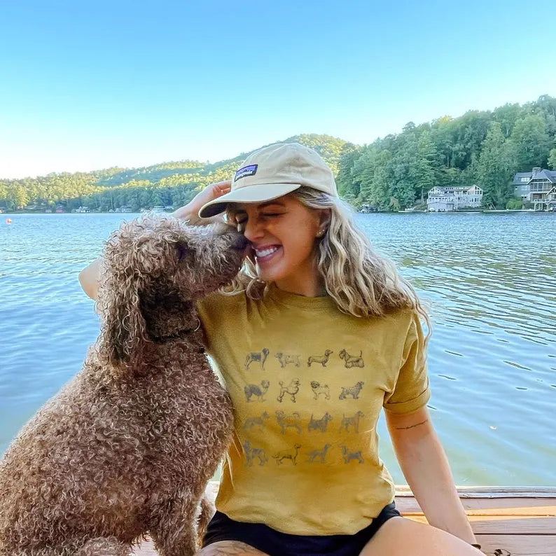 Woman in a yellow shirt with a dog by a lake