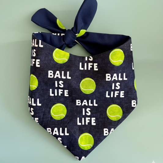 Dog bandana with 'Ball is Life' text and tennis ball pattern on a light green background