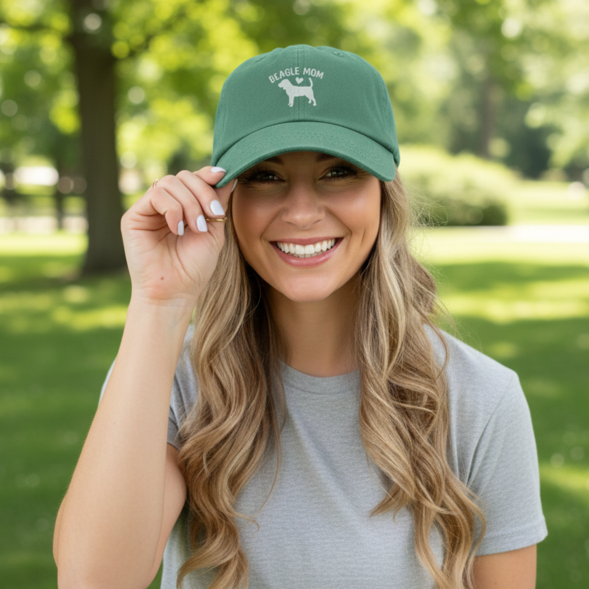 Woman wearing a green cap with 'Beagle Mom' text in a park setting