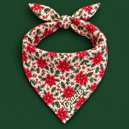 Poinsettia dog bandana with red poinsettias, green holly leaves, and red berries on a cream background, knotted and displayed on a dark green panel, with product details listed beside it including 100% recycled polyester, single-sided all-over print, double-folded edges, and OEKO-TEX certified fabric