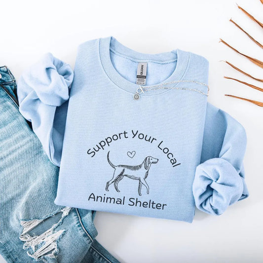 Light blue sweatshirt with 'Support Your Local Animal Shelter' text and dog illustration on a white background.